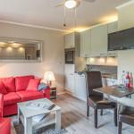 Wohnbereich mit rotem Sofa, Küchenzeile und Essplatz mit Fernseher.