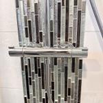 Duschbereich mit chromfarbenem Wasserhahn und Glasmosaikwand