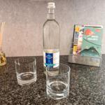 Auf der Arbeitsfläche stehen eine Flasche Mineralwasser, zwei Gläser und ein Duftspender.