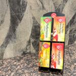 Vier Teeboxen auf einem Tisch vor einer Wand mit Muster.