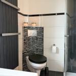 Bad mit Toilette, Dusche und schwarz-weißen Fliesen