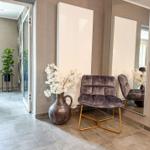 Eingangsbereich mit Sitzgelegenheit, Spiegel und Vasen mit weißen Blumen.