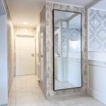 Flur mit Spiegel, Fenster und weißen Türen. Marmorierte Wände und Bodenfliesen.