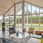 Living room with fireplace, seating, and large windows overlooking green areas.