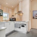 Kitchen with wooden walls, white cabinets, and modern equipment.