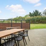 Terrace with table and chairs, lawn and forest in the background.