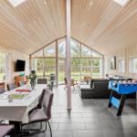 Large space with dining area, sofa, and foosball table. Wooden ceiling and large windows.