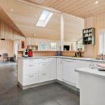Kitchen with white cabinets, granite countertop, and wood walls. Skylight and windows provide daylight.