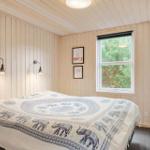 Bedroom with wooden walls, bed with elephant blanket, and window overlooking trees.