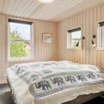 Bedroom with wooden walls, bed with elephant blanket, and two windows.