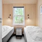 Two beds with white bedding, wooden walls, and window with view of trees.