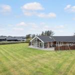 Wooden house with large garden and playground under blue sky.