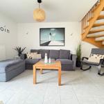 Living room with gray sofa, wooden table, and spiral staircase.