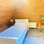 Bedroom with wooden walls, bed, nightstand, and radiator.