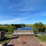 Quiet viewpoint with bridge, river, and green fields under blue sky.