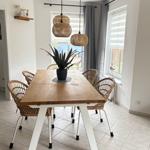 Dining room with wooden table, rattan chairs, and three pendant lamps.