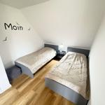 Two beds in an attic room with wooden floor and wall decoration.