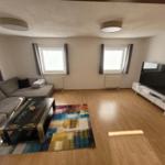 Living room with sofa, TV, and wooden floor