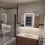Bathroom with shower, sink, and illuminated mirror