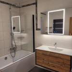 Bathroom with shower, sink, and illuminated mirror.