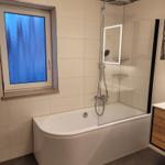 Bath with bathtub, shower, and window with blue glass.