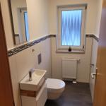 Bathroom with sink, toilet, and window with frosted glass.