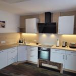 Kitchen with white cabinets, wooden countertop, and built-in stove.