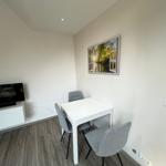 Kleiner Raum mit Tisch, Stühlen, Fernseher und Wandbild.