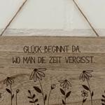 Holzschild mit Gravur: Glück beginnt da, wo man die Zeit vergisst. Mit Blumenmotiven.