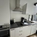 Küche mit weißen Schränken, Induktionskochfeld und Blick auf Balkon.