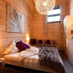 Schlafzimmer mit Holzwand, Bett, Nachttisch und Kleiderschrank.