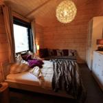 Schlafzimmer mit Holzwand, Bett, Fenster und Lampen.