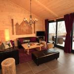 Wohnzimmer mit Holzwänden, Ledersofa, Holztisch und Terrasse mit Blick.