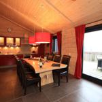 Essbereich mit Holztisch, schwarzen Stühlen und Kamin. Durchgang zur Küche und Terrasse.