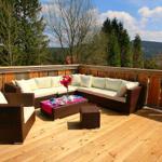 Terrasse mit Sitzgruppe, Tisch und Blick auf Wald und Berge.