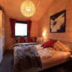 Schlafzimmer mit Holzwand, Bett, Fenster, Nachttisch und Decke.