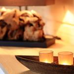 Drei brennende Kerzen in einem Holzboot auf einer Arbeitsfläche. Im Hintergrund steht eine Skulptur.