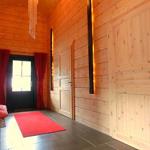 Holzgetäfeltes Foyer mit rotem Teppich, Tür und Wandlampen.