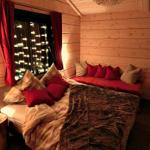 Schlafzimmer mit Holzwand, Bett, Kissen und Fenster mit Lichterkette.