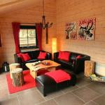 Wohnzimmer mit Holzwänden, zwei schwarzen Sofas, rotem Teppich und Holztisch.