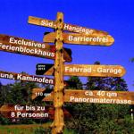 Holzschild zeigt Wegweiser zu Ferienhaus, Sauna, Garage und Terrasse.