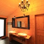 Badezimmer mit zwei Waschbecken, Spiegel und Kronleuchter an Holzwänden.