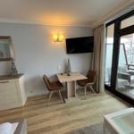 Wohnraum mit Esstisch, Fernseher und Balkon mit Blick auf Schnee