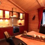 Küche mit roten Schränken, Holzwand und Esstisch mit Kerzen.