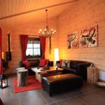 Wohnzimmer mit Holzwänden, roten Vorhängen und Ledersofa. Es gibt einen Kamin und Wandkunst.