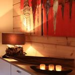 Holzwand mit abstraktem Gemälde, Lampe auf Sideboard und Kerzen in Holzschale.