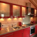 Küche mit roten Schränken, Edelstahlspüle und integriertem Herd.