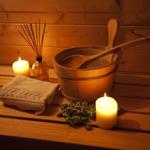 Holzbank mit Wasserbucket, Kerzen und Steinen in Sauna