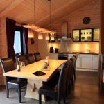 Essbereich mit langer Tisch und Stühlen, Küche und Kaminofen im Holzhaus.