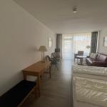 Ein Schlafzimmer mit einem Bett, einem Schreibtisch und einem Sofa. Durchgang zum Balkon mit Blick.